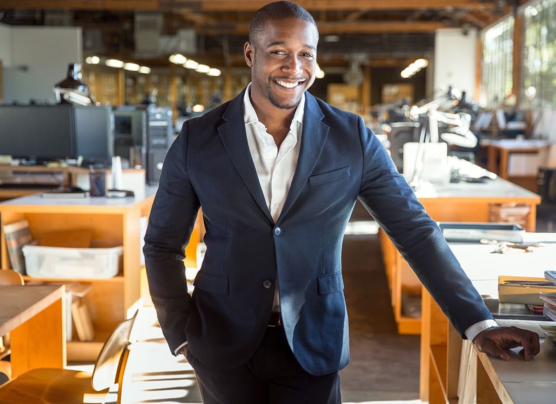 Business Insurance - New Business Owner Standing Proud at Workplace Office